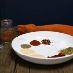 A front view of a bowl that has piles of the spices that make up this Cajun seasoning blend.