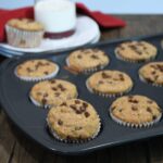 A close up of applesauce banana muffins with chocolate chips in a muffin pan.