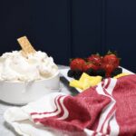 A bowl filled the strawberry cream cheese fruit dip recipe wih a graham cracker sticking out the top.