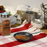 A small dish that has the homemade creole seasoning blend in it with more in a jar behind the dish.