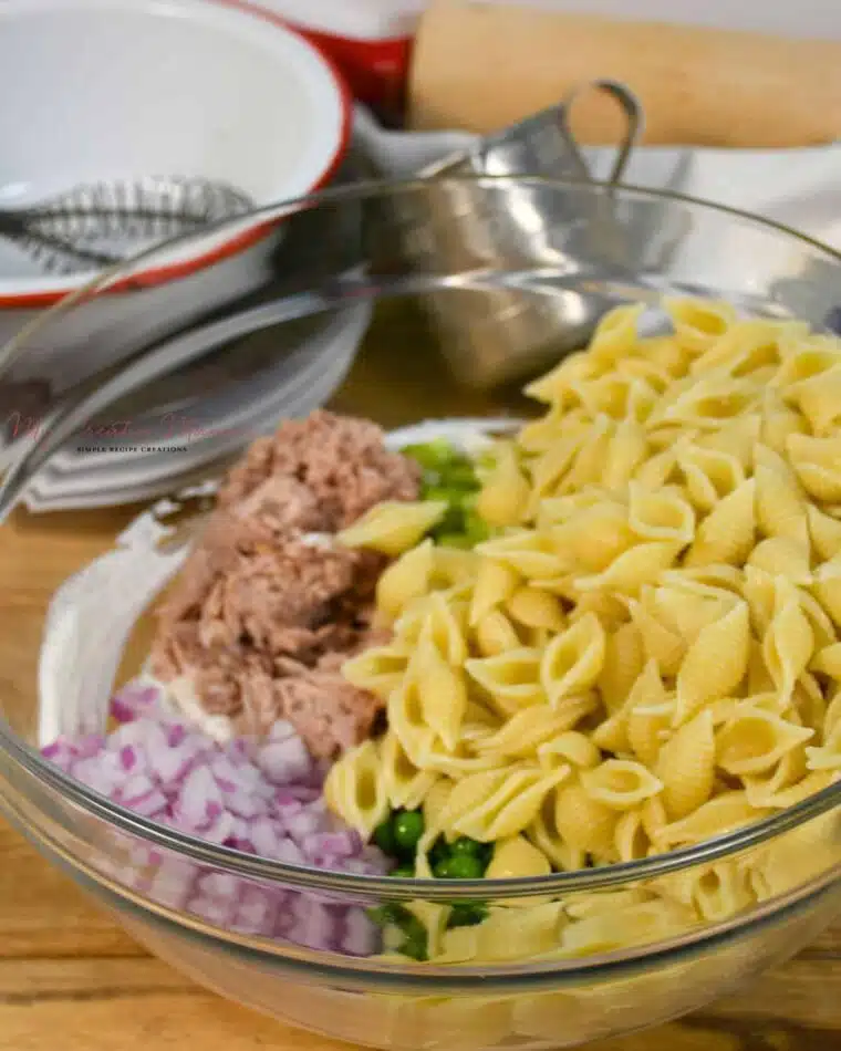 A mixing bowl filled with the ingredients to make the cold tuna pasta salad recipe.