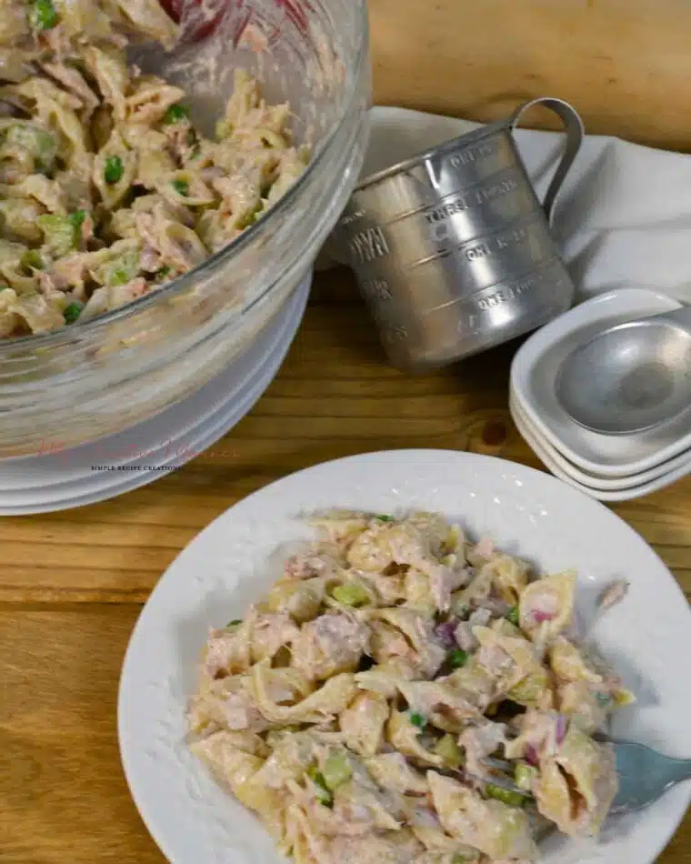 A closer look down on a bowl and plate with the cold pasta salad with tun recipe.