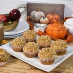 Pumpkin muffins with crumb topping on a white platter.